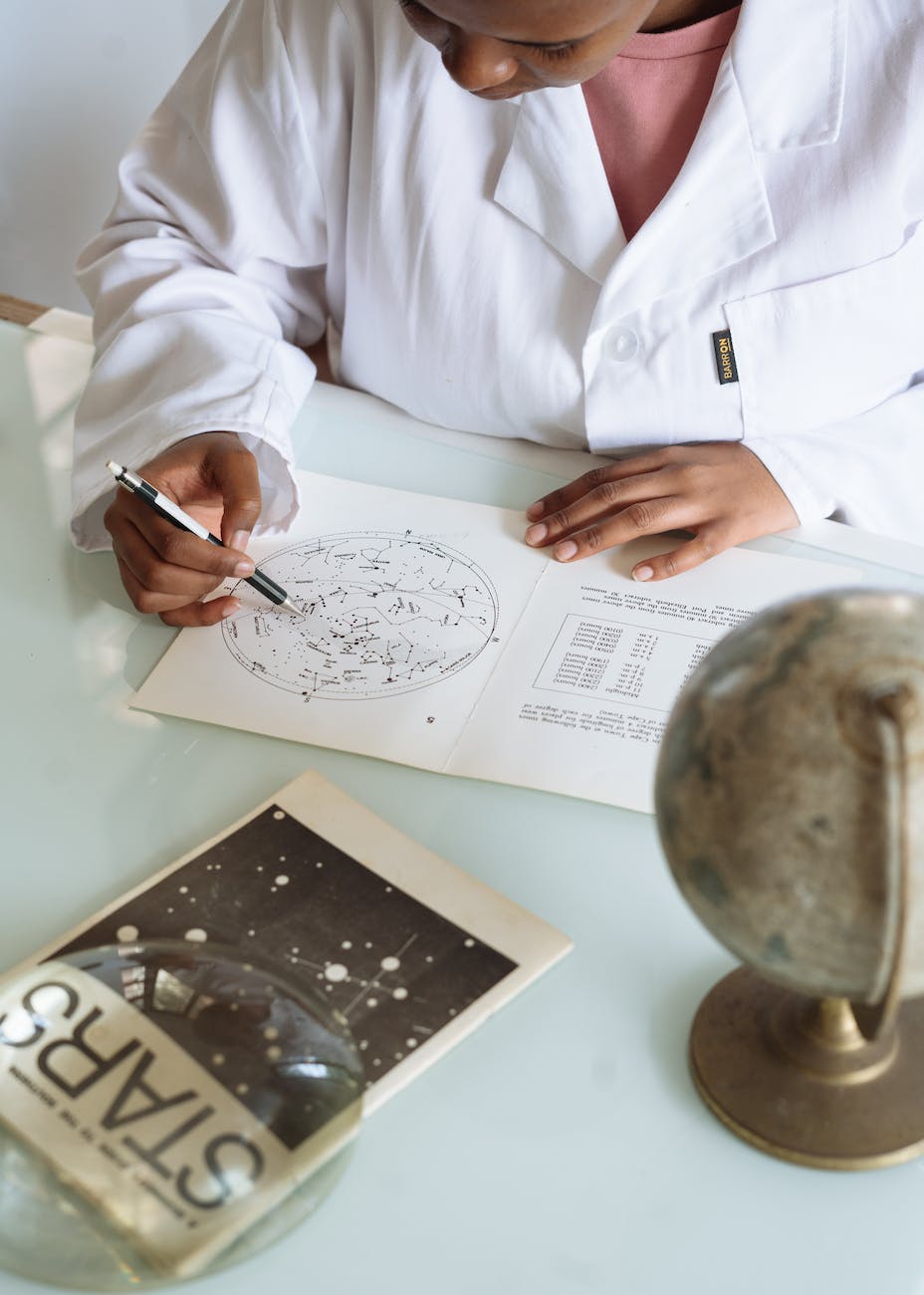 from above of ethnic astronomer studying astronomical map in research center